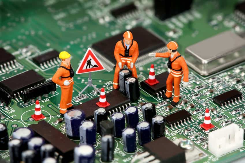 Miniature workers repairing a motherboard